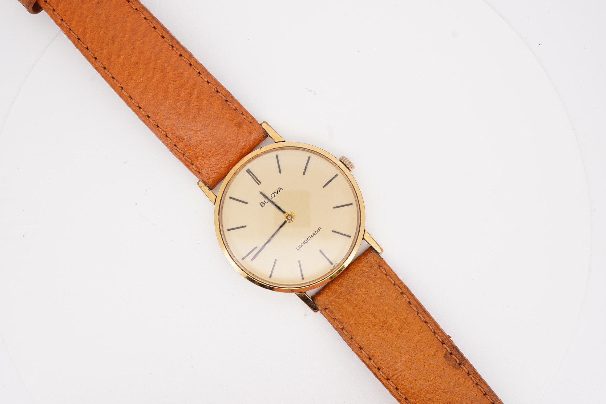 A gentleman's steel and gold plated Bulova Longchamp manual wind wrist watch, with baton numerals, case diameter 33mm, on a tanned leather strap.